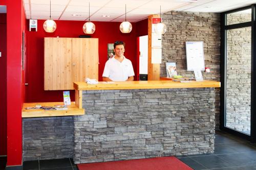 a man standing behind a bar in a restaurant at Résidence Néméa L'Aigle Bleu in Briançon