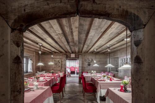 a large dining room with tables and red chairs at Hotel La Perla: The Leading Hotels of the World in Corvara in Badia