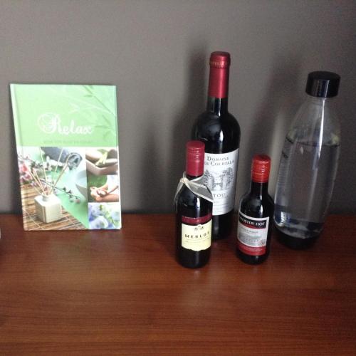 three bottles of wine sitting on a wooden table at Guesthouse De Steenberg tweepersoonskamer met grote badkamer, kitchenette en tuinzicht op de eerste verdieping in Geel