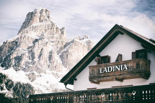 a sign on a building in front of a mountain at Berghotel Ladinia in Corvara in Badia