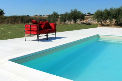 a red chair sitting on a patio next to a swimming pool at Casa Sbrizza in Rosolini