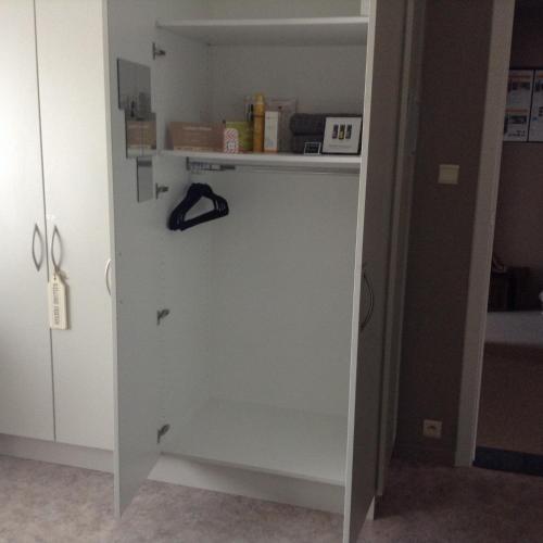 a white cabinet in a room with a shelf at Guesthouse De Steenberg tweepersoonskamer met grote badkamer, kitchenette en tuinzicht op de eerste verdieping in Geel