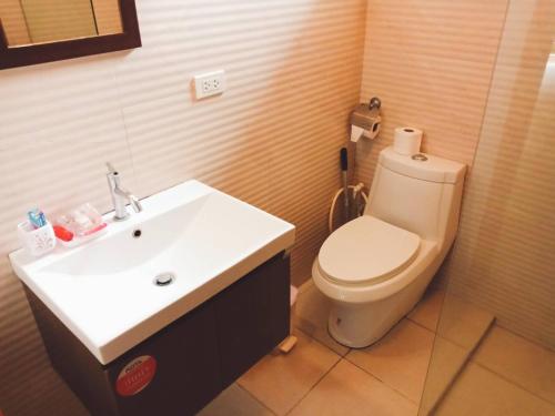 a bathroom with a white toilet and a sink at Hibiscus Cottage in Ban Dan Kao