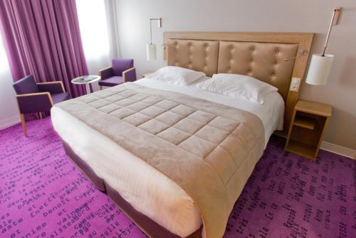um quarto com uma cama grande e um tapete roxo em Hôtel Anne De Bretagne em Rennes
