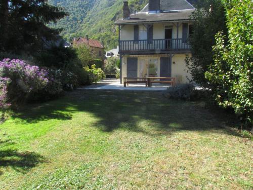 a house with a bench in the middle of a yard at Le domaine des 3 marmottes Chambres d' hôtes in Cierp
