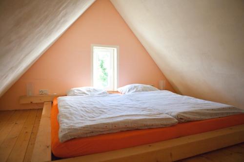 1 cama con colchón naranja en una habitación con ventana en FeWo M&M, en Mirow