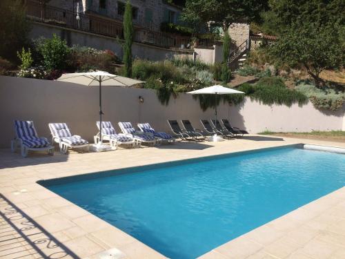 a swimming pool with chairs and umbrellas at Luxury country house with heated private pool in Courniou
