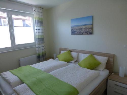 ein Schlafzimmer mit einem Bett mit zwei grünen Kissen in der Unterkunft Residenz Windjammer Whg 12 in Cuxhaven