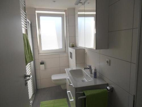 ein Bad mit einem Waschbecken, einem WC und einem Fenster in der Unterkunft Residenz Windjammer Whg 12 in Cuxhaven