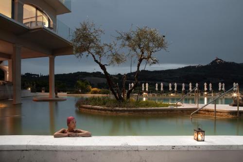 a man laying in the water in a swimming pool at La Posta Hotel & Thermal Spa in Bagno Vignoni