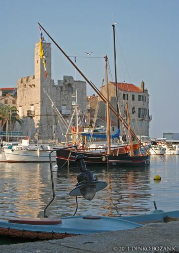 a light on a boat in the water with boats at Apartments Popaj in Komiža