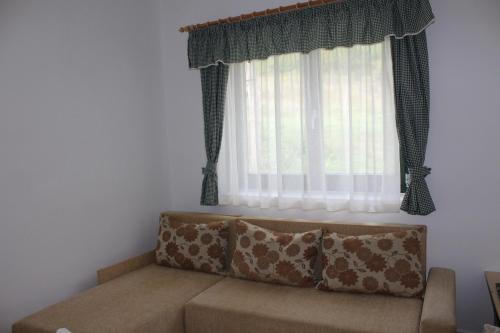 a couch in a living room with a window at Patrícia Pihenőház in Alsónána
