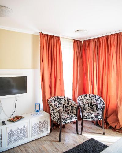 a living room with two chairs and a tv at Pensiunea Un Baiat si o Fata in Cîmpulung
