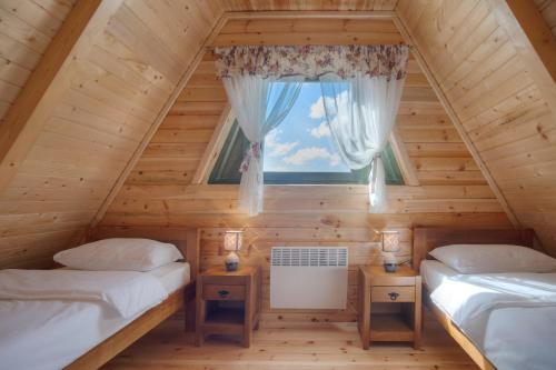 two beds in a log cabin with a window at Woodland in Žabljak
