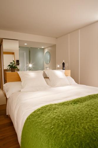 a large white bed with a green blanket on it at Hotel Echaurren Relais & Châteaux in Ezcaray