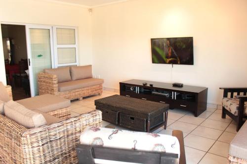 a living room with couches and a tv on the wall at Vista Bonita Apartments in Mossel Bay
