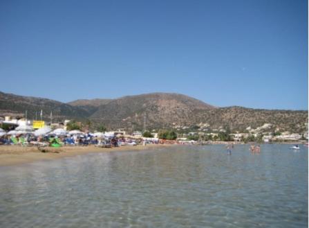a beach with a bunch of tents and people in the water at 4S Beach Superior Apartments in Stalida