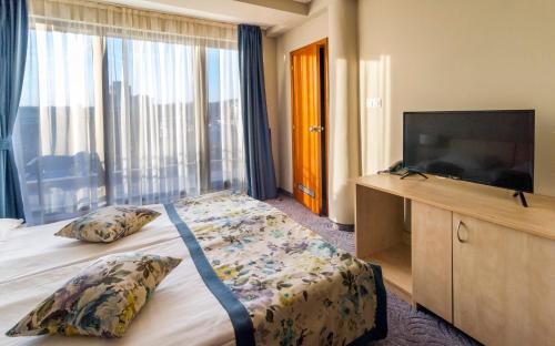 a hotel room with a bed and a flat screen tv at Plaza Hotel in Varna City