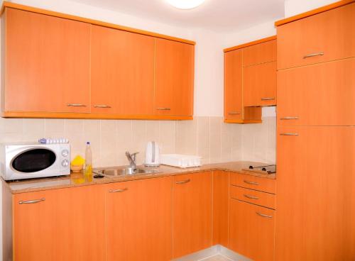 eine Küche mit Holzschränken und einer Mikrowelle in der Unterkunft Holiday apartments in Haifa