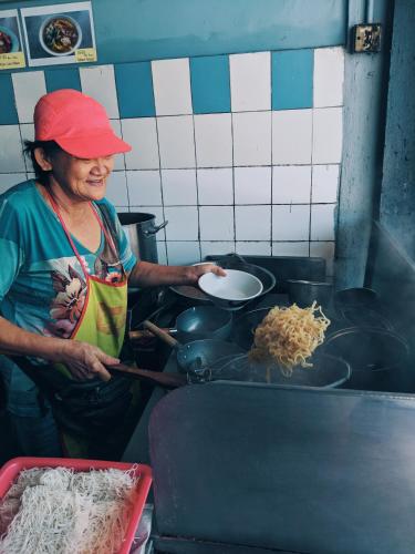 a woman is preparing food in a kitchen at Hin Loi Guesthouse in Kota Kinabalu