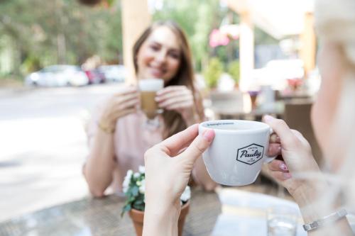a woman holding up a cup of coffee at Kubija Hotel and NatureSpa in Võru