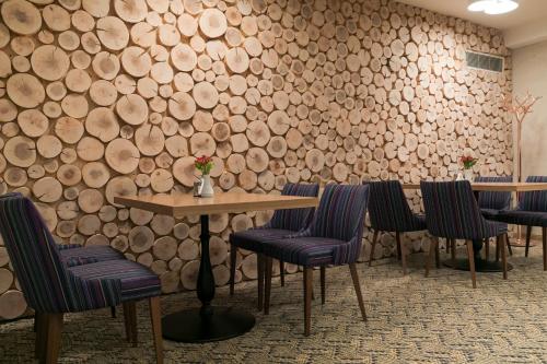 a table and chairs with a wall of logs at Kubija Hotel and NatureSpa in Võru