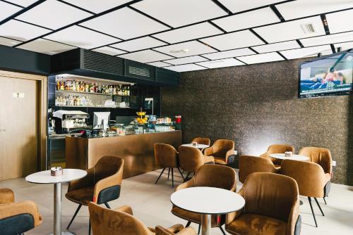 Un restaurante con mesas y sillas y un bar. en Hotel Egnatia, en Tirana