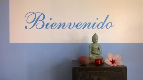 a buddha statue sitting on a table in front of a sign at Birdcage Gay Men Resort and Lifestyle Hotel in Playa del Ingles