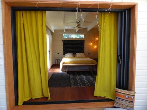 1 dormitorio con cortinas amarillas y 1 cama en La Kaz Nana Sakifo - Maison d'hotes, en Saint-Paul