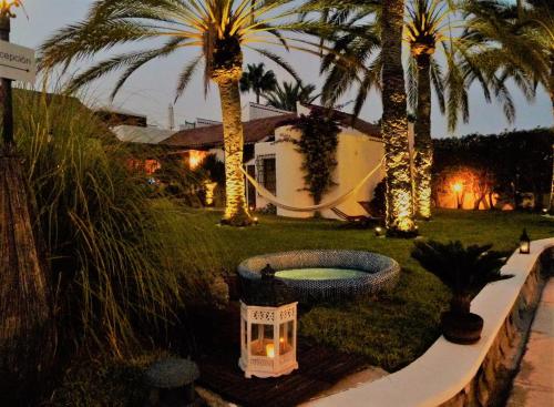 a yard with palm trees and a house with a fountain at Birdcage Gay Men Resort and Lifestyle Hotel in Playa del Ingles