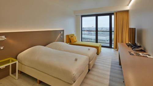 a hotel room with two beds and a desk at Corbie Lommel Ring in Lommel
