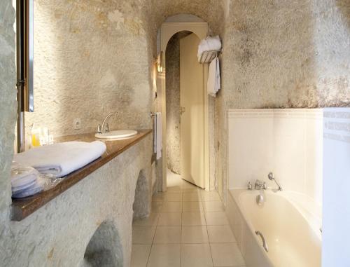 een badkamer met een bad, een wastafel en een bad bij Hotel Les Hautes Roches in Rochecorbon