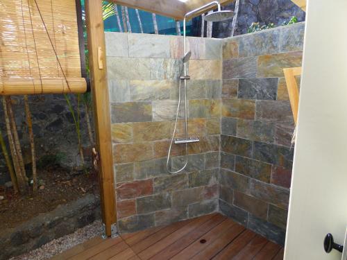 a shower in a bathroom with a stone wall at La Kaz Nana Sakifo - Maison d'hotes in Saint-Paul