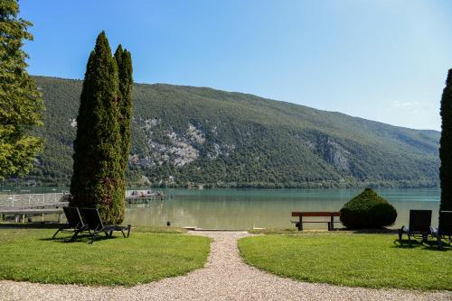 a park with a bench and a lake and mountains at Novalaise Plage in Novalaise