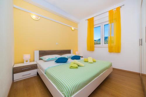a bedroom with a bed with blue pillows and a window at Apartment Marino in Kaštela