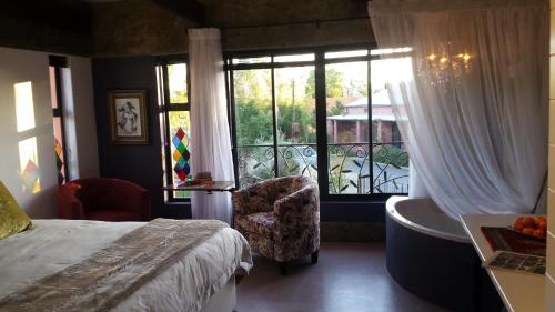 a bedroom with a bed and a window and a chair at Absolute Castillo in Riebeek-Kasteel