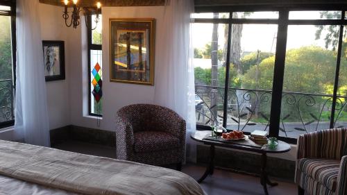 a bedroom with a bed and a chair and a balcony at Absolute Castillo in Riebeek-Kasteel