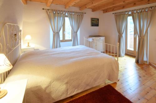 a bedroom with a large white bed and windows at Relais del Sosto in Olivone