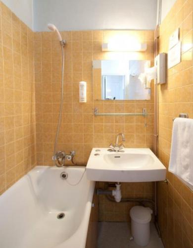 a bathroom with a sink and a bath tub and a sink at The Old Hotel Ravel Centre in Clermont-Ferrand