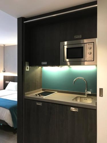 a kitchen with a sink and a microwave at HG City Suites Barcelona in Barcelona