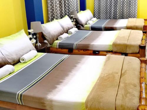 a group of three beds in a room at Prosperity Inn in Vigan