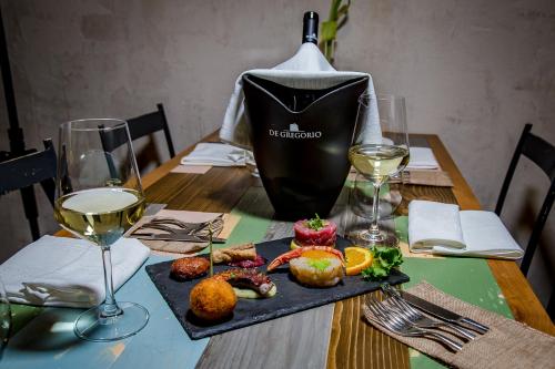 a table with a plate of food and glasses of wine at Cantine De Gregorio Suites in Sciacca