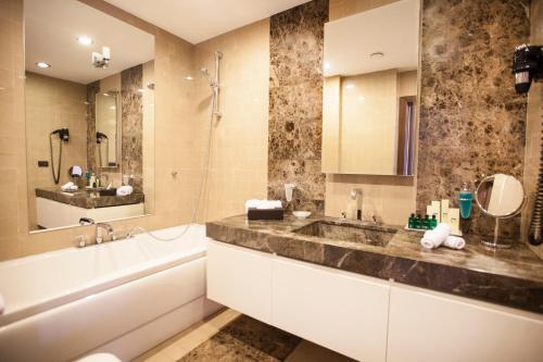 a bathroom with a sink and a tub and a mirror at Chinar Hotel & Spa Naftalan in Naftalan