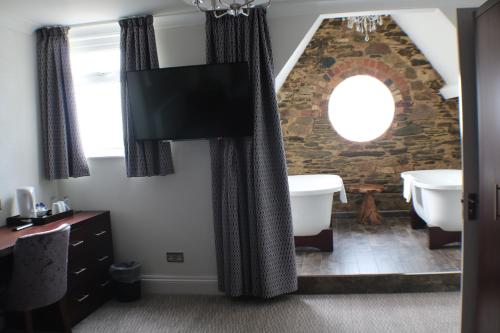 a bathroom with a stone wall and a tub and a sink at Legacy Hotel Victoria in Newquay