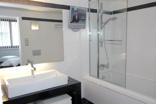 uma casa de banho branca com um lavatório e um chuveiro em Esplanada Studios em Genk