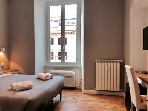 1 dormitorio con cama, ventana y escritorio en Audrey's Roman Holidays - Rome Suites & Rooms, en Roma