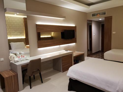 a bedroom with a bed and a desk with a mirror at Novena Hotel Bandung in Bandung