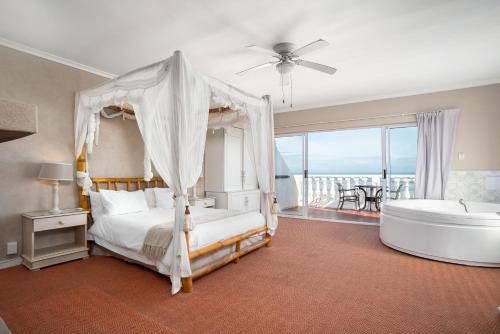 The Beach Villa في مليكبوستراند: غرفة نوم بسرير وحوض استحمام وغرفة نوم مطلة
