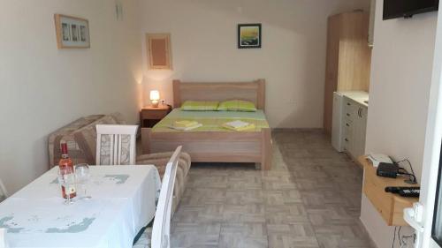 a small bedroom with a bed and a table and chairs at Apartman Pijavica in Bijela