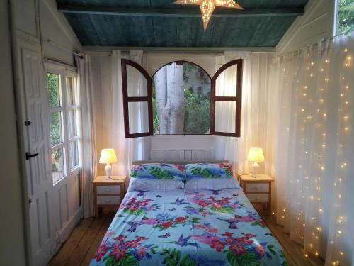 1 dormitorio con 1 cama y 2 ventanas con luces en El Jardín de las Hadas, en Turre